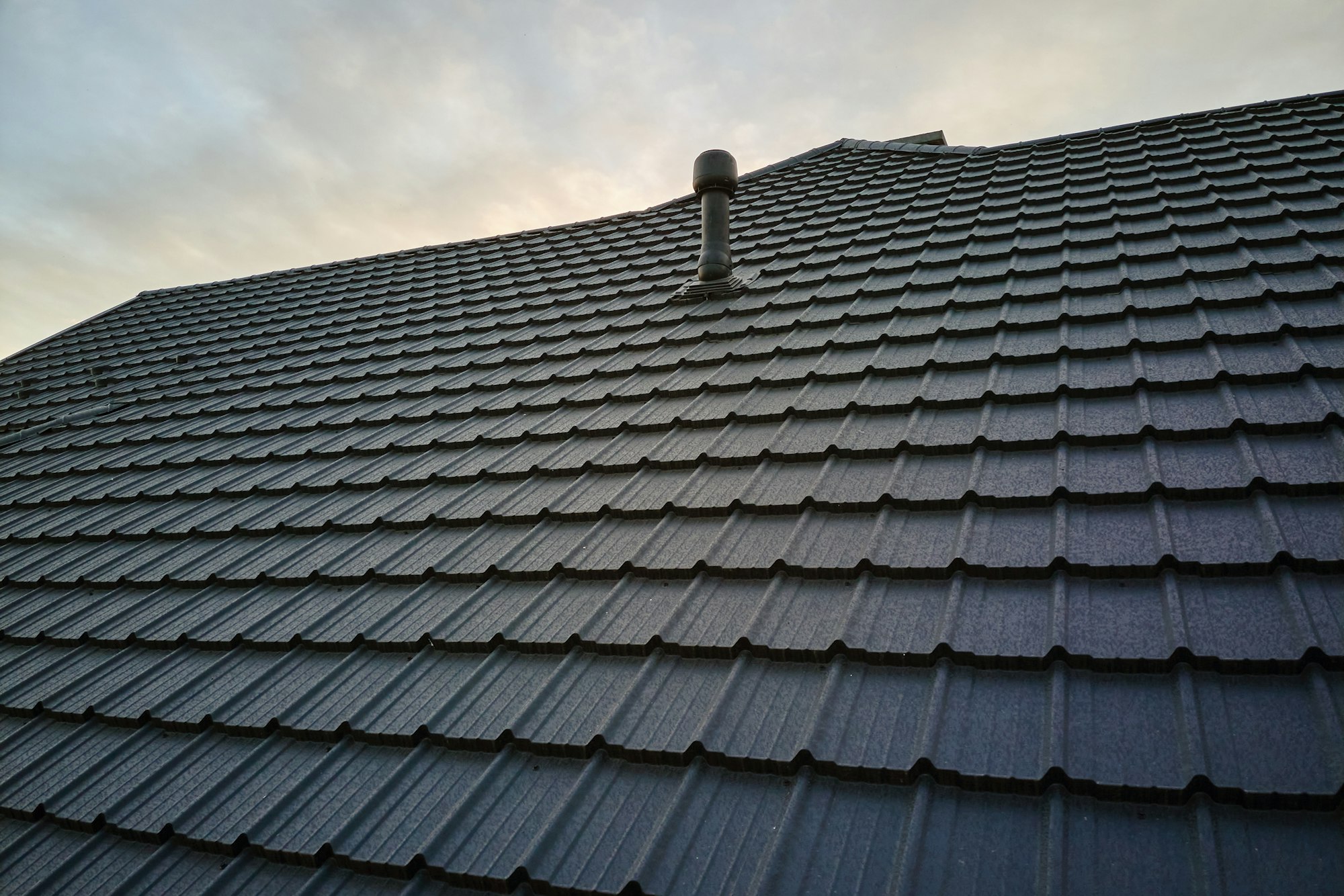 Closeup of house roof top covered with metallic shingles.Tiled covering of building
