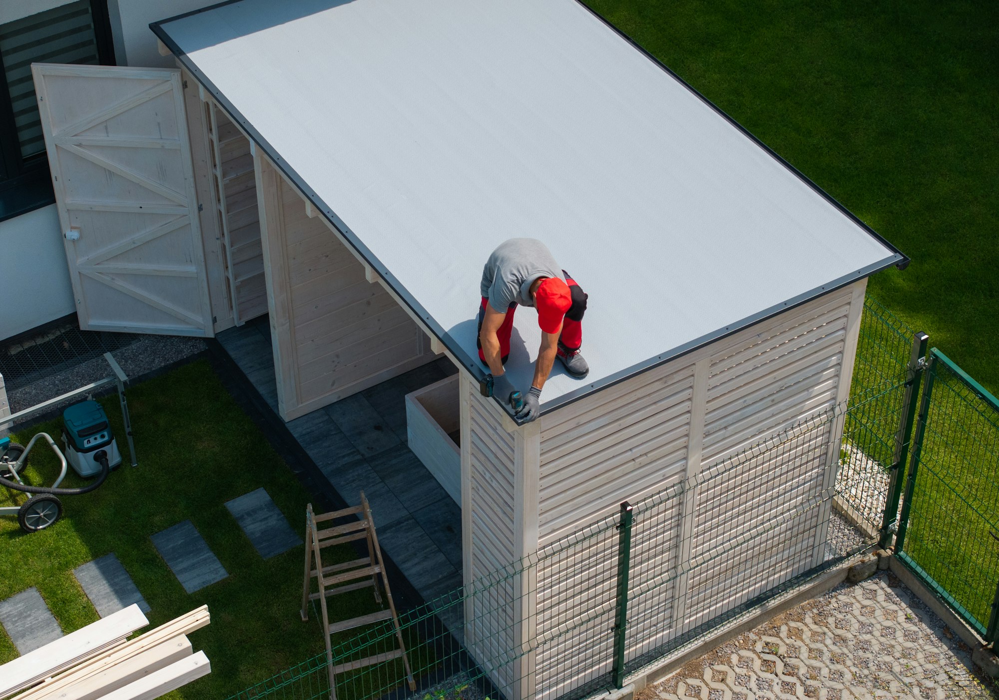 Worker Installing Roof on Wooden Shed
